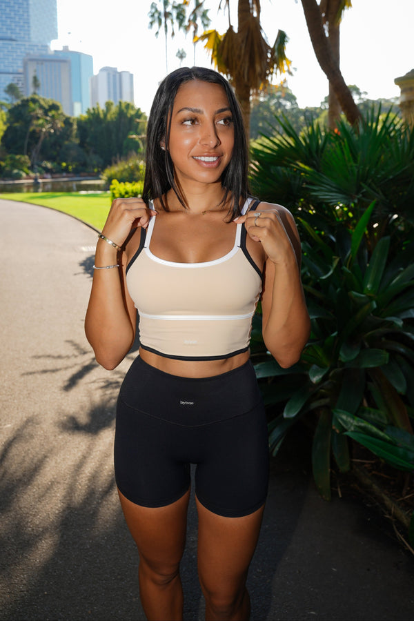 Model wearing The Original Singlet in Vanilla Bean, showcasing an in-built bra, sculpted fit, and bold 3-colour combo, perfect for workouts, brunch dates, and everyday wear.